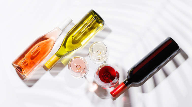 different types of wine in bottles and glasses against white background