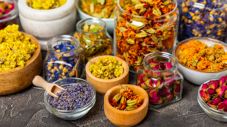 An assortment of dried floral teas in glass and wooden containers