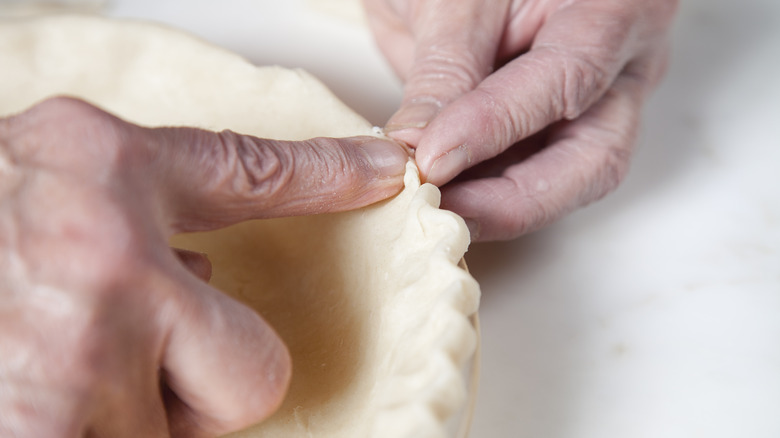 A person crimping a pie crust.