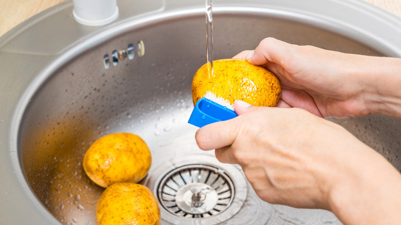 Washing potatoes under running water