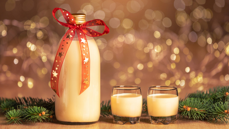 A bottle of homemade eggnog with two glasses full next to it