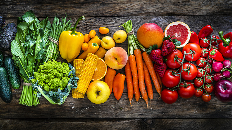 Colorful rainbow of fruits and veggies on dark wood