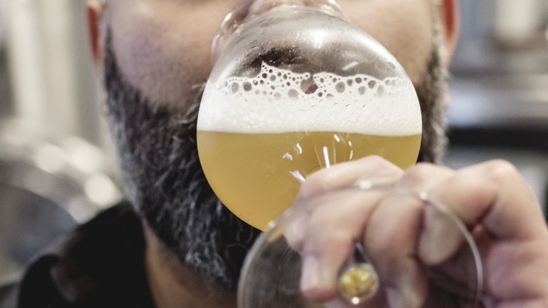 A person drinking a glass of beer.