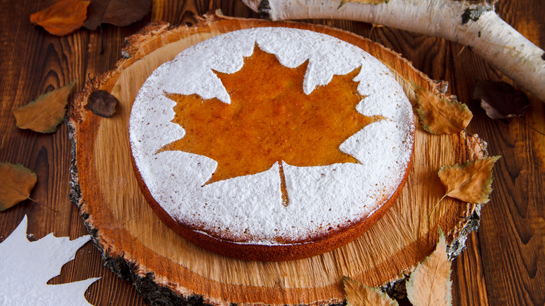 Cake dusted with powered sugar to form a maple leaf in negative space.