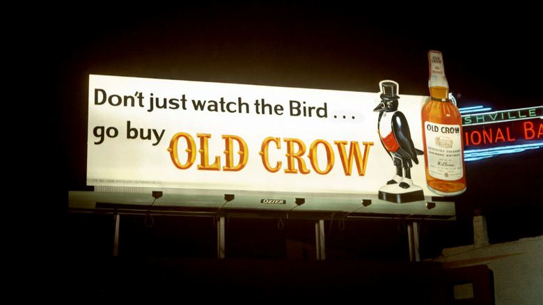 ﻿﻿A vintage Old Crow billboard from the 1970s, featuring a bird mascot and a bottle of bourbon