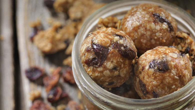 A glass jar full of energy balls on a table full of dry ingredients