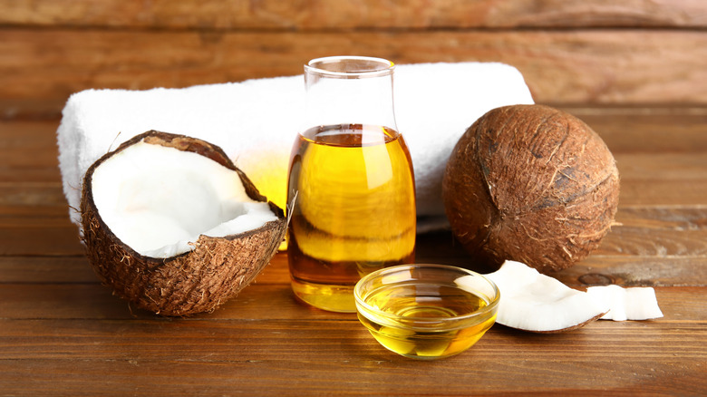 Small containers of coconut oil near cracked open coconuts