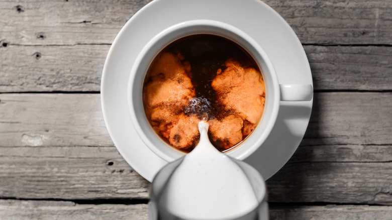 Milk being poured into coffee