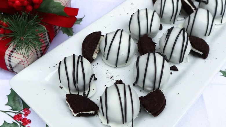 white chocolate-dipped Oreo balls on a white tray with a Christmas present