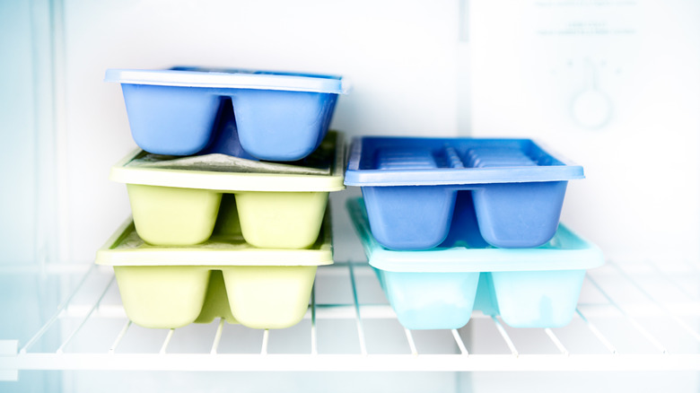 Blue and yellow ice cube trays inside a freezer