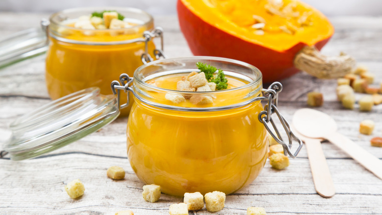 Glass jars of squash soup with croutons