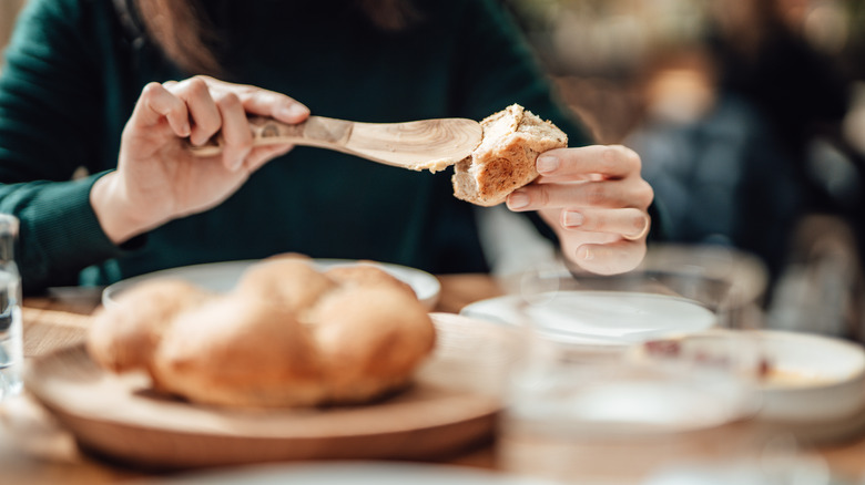 Person spreading butter on bread in restaurant