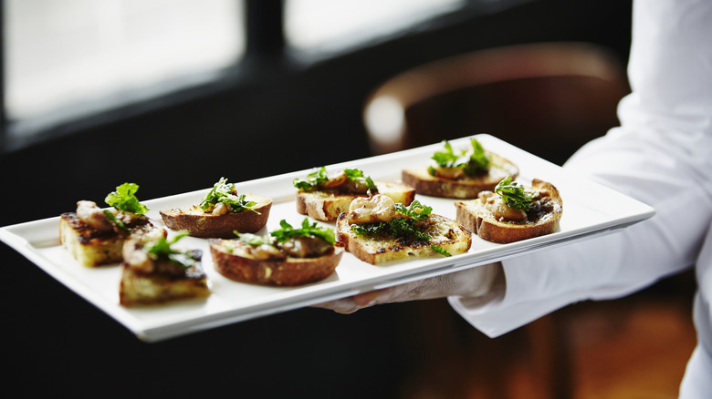 Waiter holding plate of appetizers