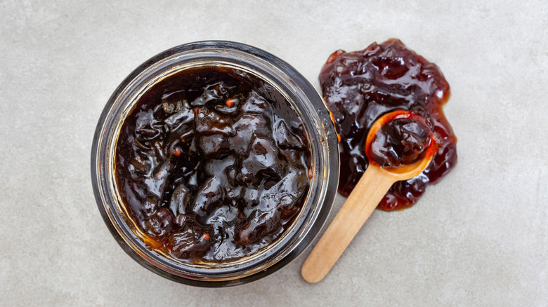 Onion jam in a jar with a small wooden spoon