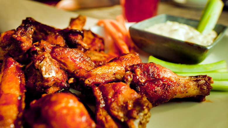 plate of chicken wings with sauce and celery in background