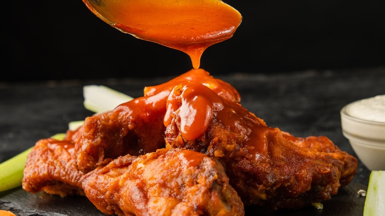 sauce being poured over chicken wings