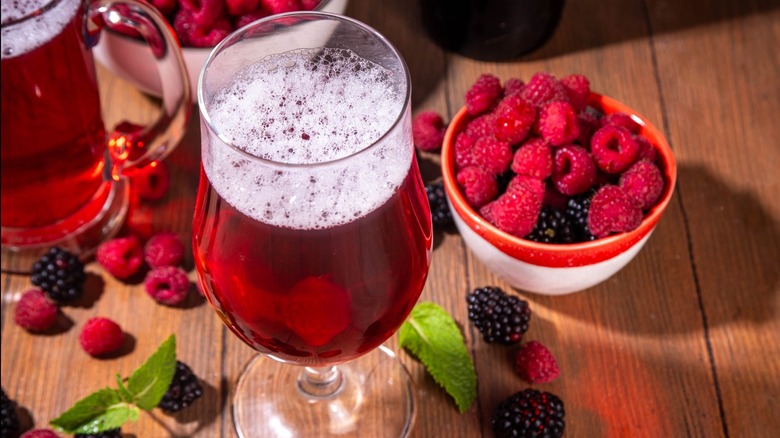 A glass of beer with bowl of raspberries