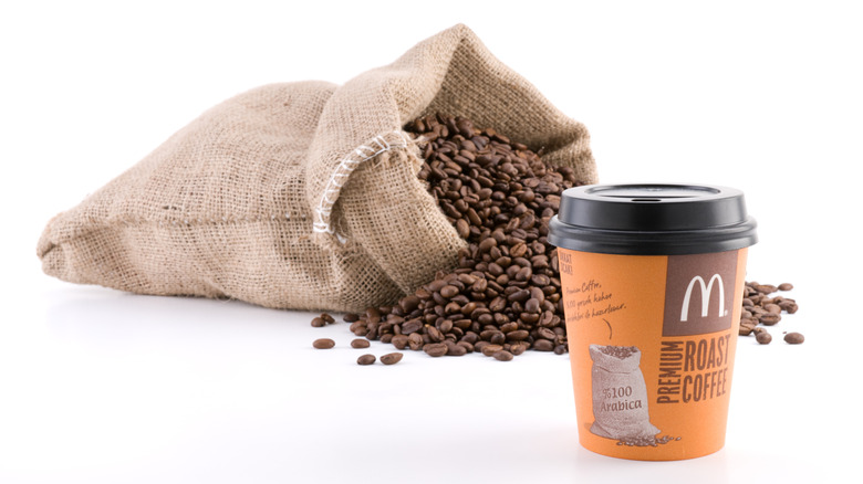 A McDonald's coffee cup in front of a sack of coffee beans