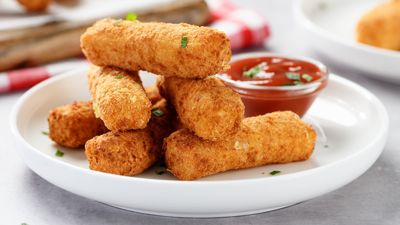 a stack of mozzarella sticks with dipping sauce