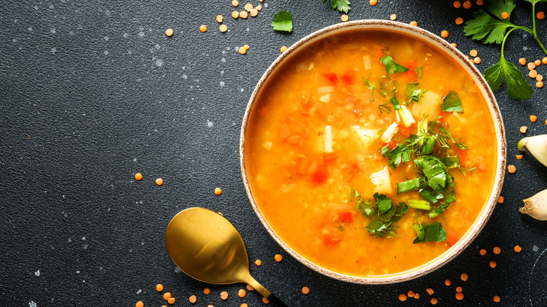 a bowl of red lentil soup topped with cilantro on a black table