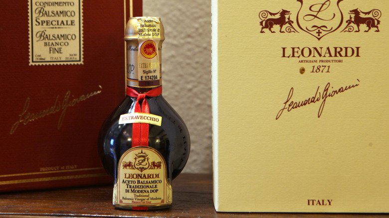 A small, round bottle of traditional balsamic vinegar on a wooden shelf