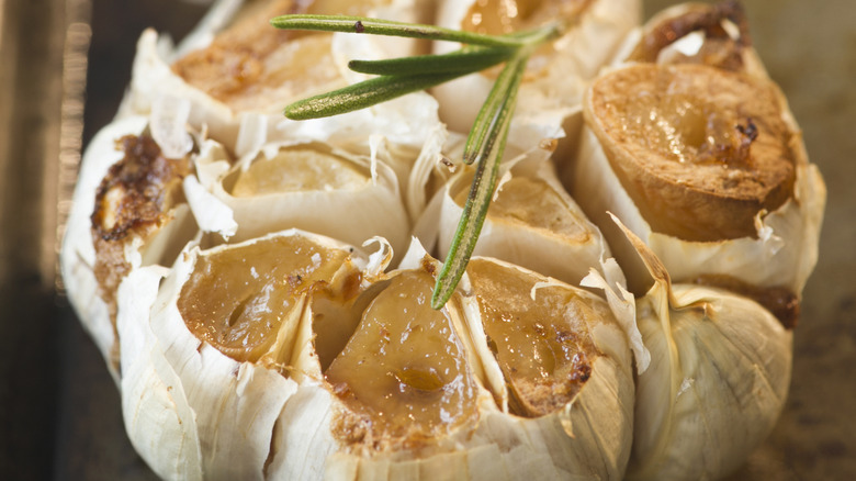 Whole roasted garlic bulb with the top cut off showing the cloves