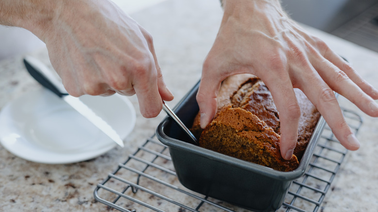 Man takes slice of pumpkin bread from loaf pan