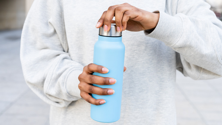 A woman opening a reusable water bottle