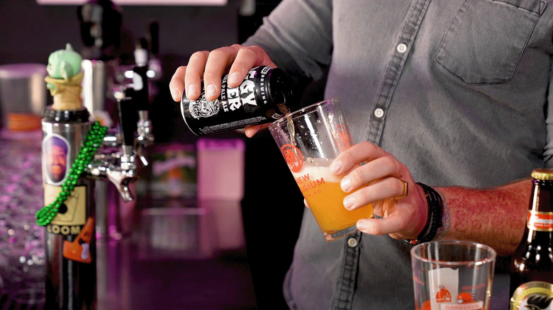 Man pouring can of beer into pint glass