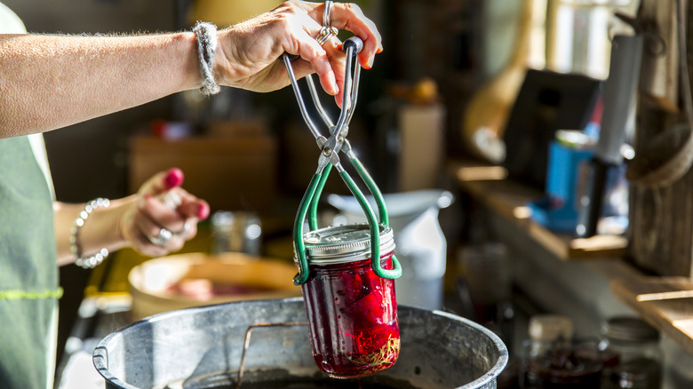 A person canning food in a mason jar