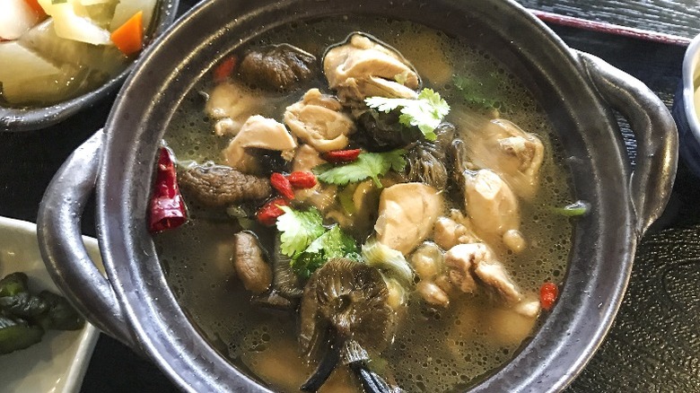 A pot of Japanese soup with chicken and vegetables.